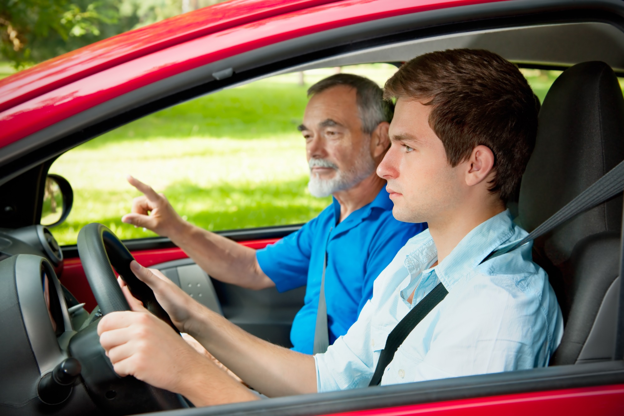 Teenager learning to drive with his driving instructor